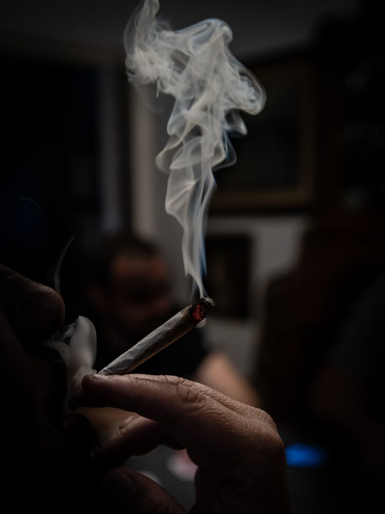 Close-up Of Person Smoking Cigarette In Dark