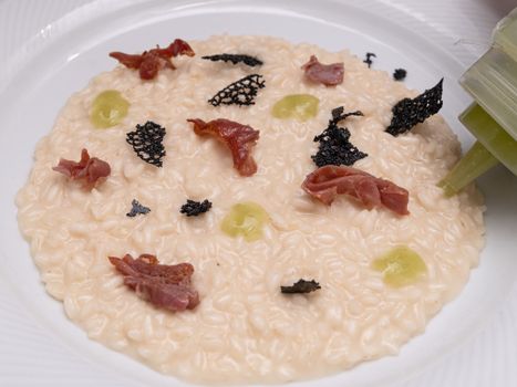 A delectable risotto dish garnished with prosciutto, truffle, and green sauce.