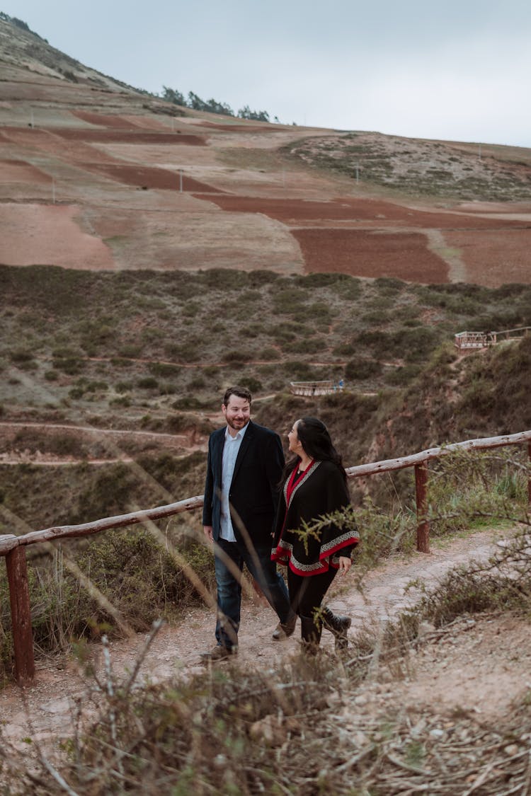 Couple Walking On Footpath Near Hill