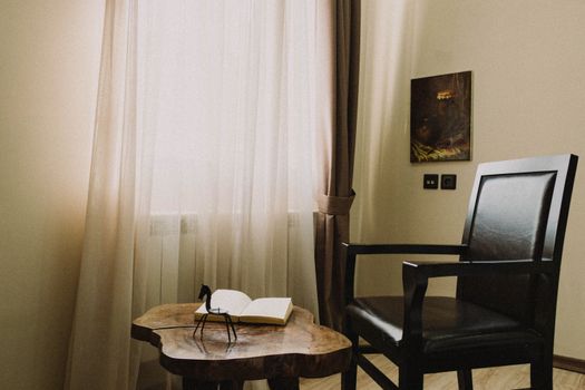 A tranquil reading corner with a chair, table, and book by a sunlit window.