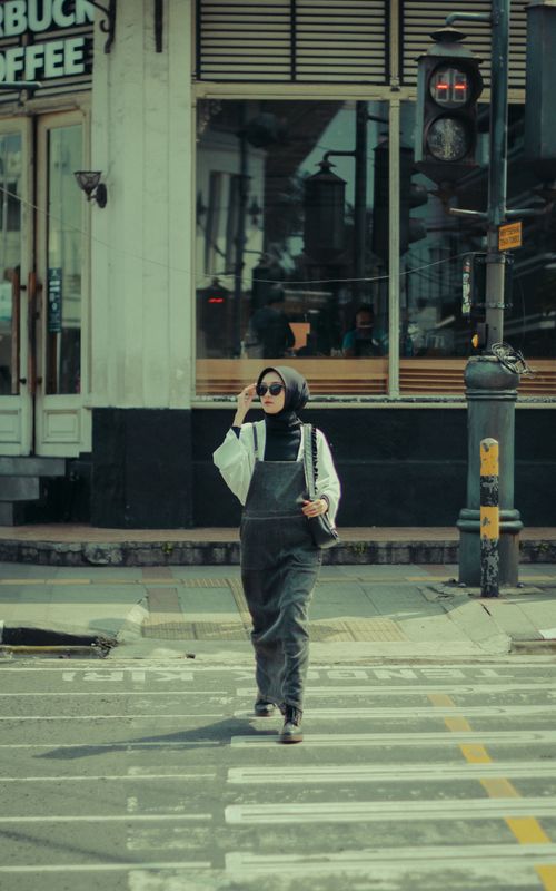 Free Woman in hijab confidently walking on city crosswalk, blending fashion with urban vibe. Stock Photo