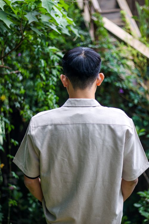 Free Portrait of a man with black hair, standing in a lush garden, view from behind. Stock Photo