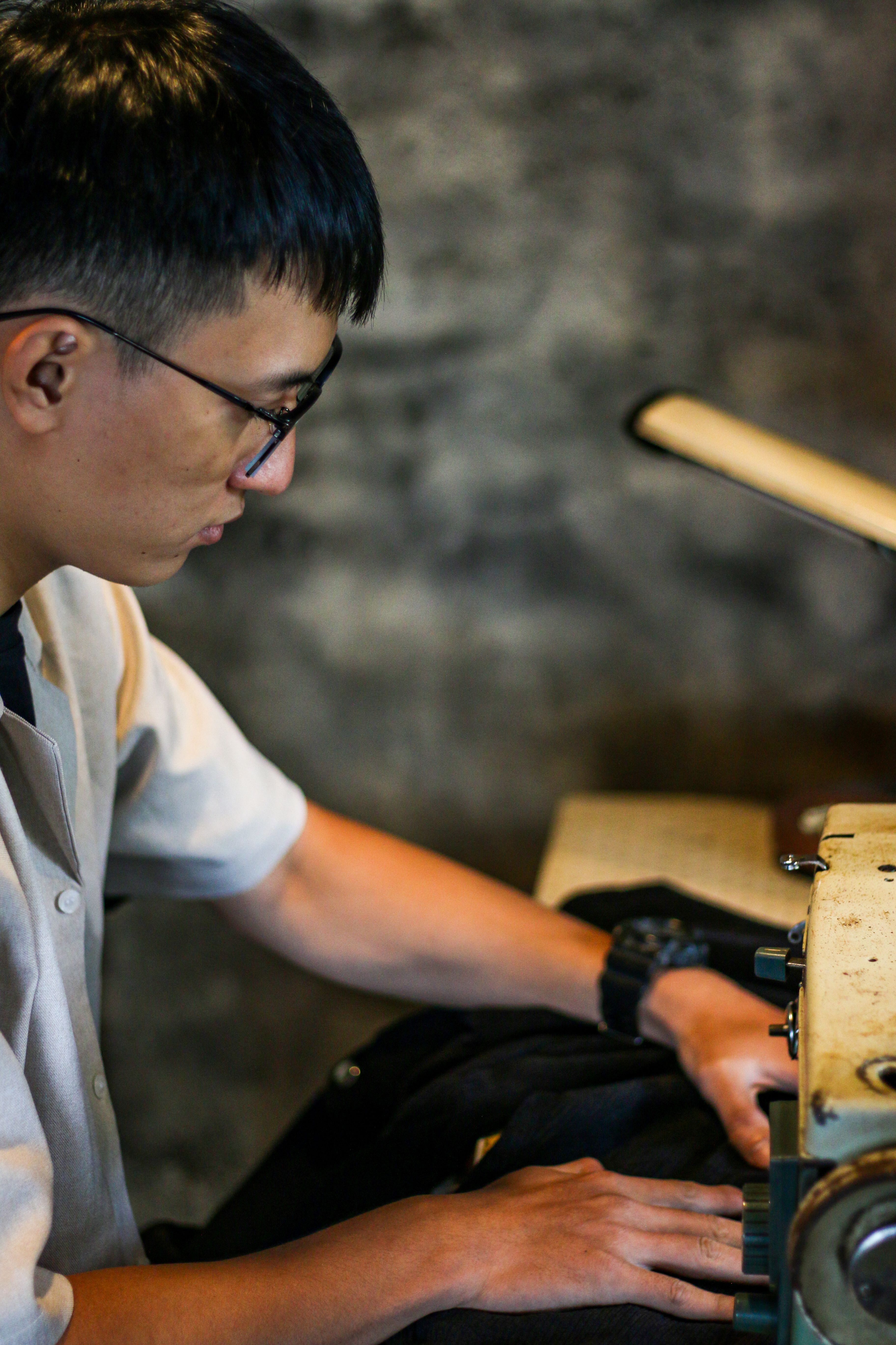 Focused young man using sewing machine indoors, showcasing craftsmanship.