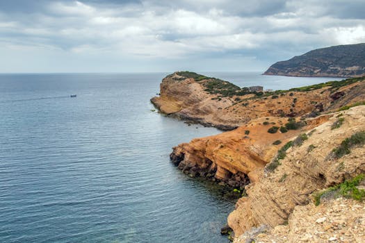 Beautiful view of a rugged coastline with dramatic cliffs and a calm sea under a cloudy sky.