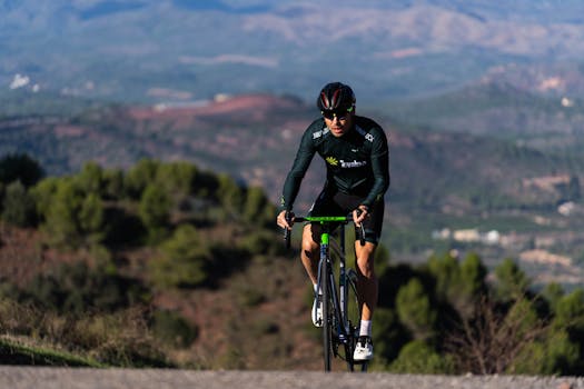 A cyclist wearing sportswear climbing a mountain road amidst a scenic landscape, embodying endurance and adventure.