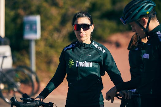 A group of cyclists in sportswear, wearing sunglasses, preparing for an outdoor ride on a sunny day.