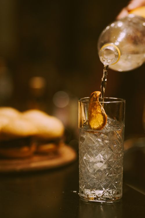 Free A drink being poured into a glass with a slice of fruit, creating a refreshing beverage scene. Stock Photo