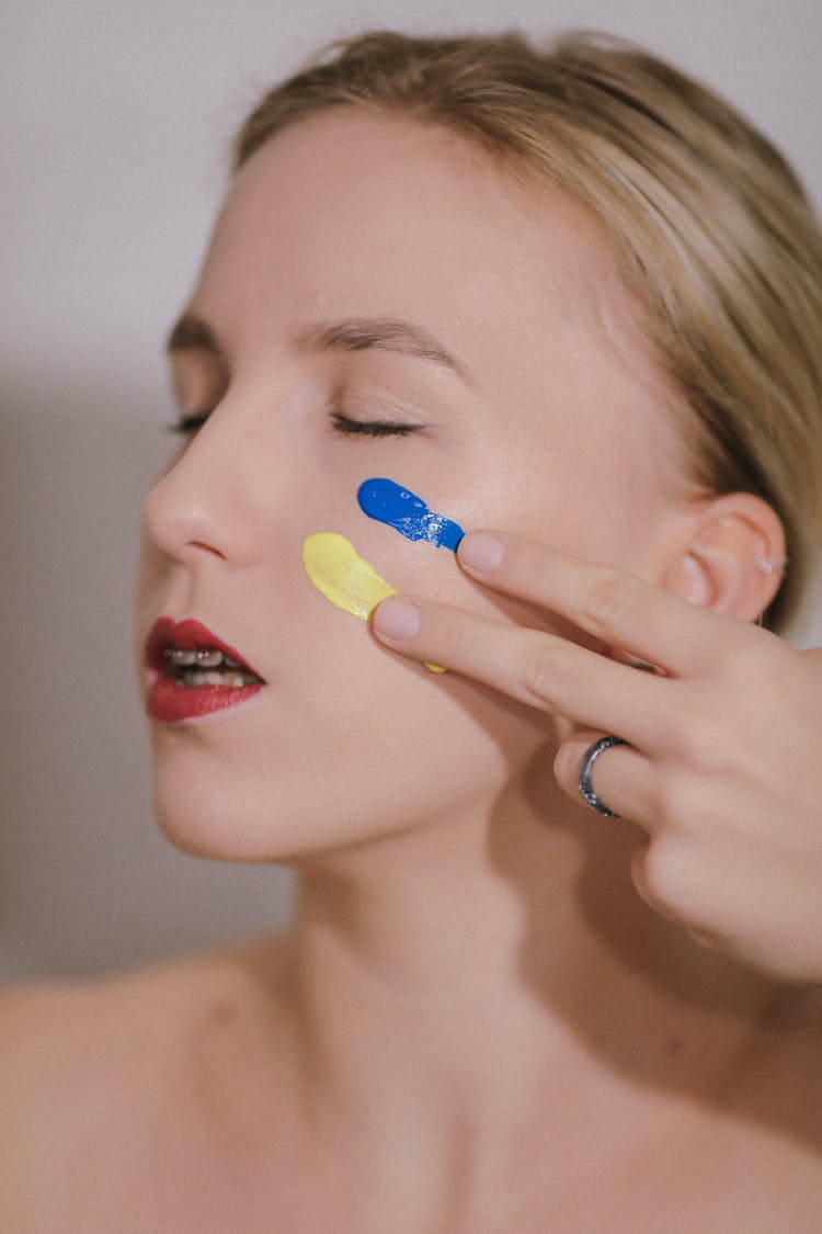 Woman Painting Flag Of Ukraine On Cheek