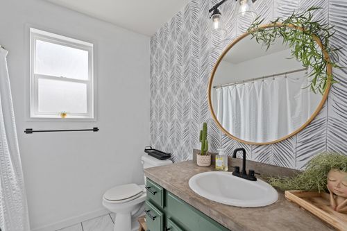 Free Contemporary bathroom with sleek design featuring mirror, green accents, and decorative plants. Stock Photo