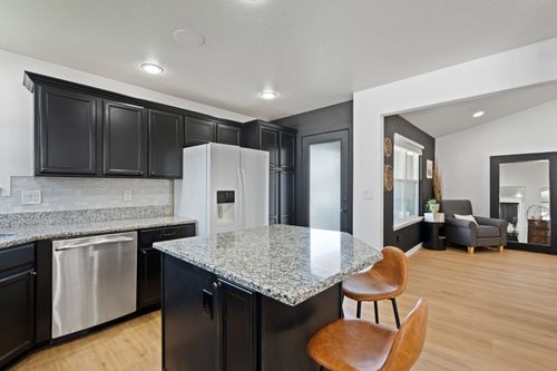 Free Sleek modern kitchen featuring granite countertops, black cabinets, and an open design. Stock Photo