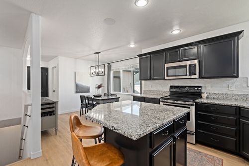 Free Sleek modern kitchen featuring granite countertops and dark cabinetry under soft lighting. Stock Photo