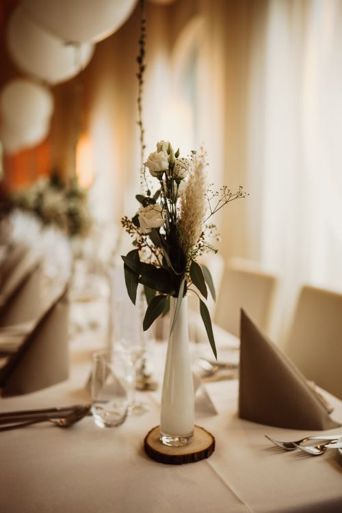 Free Close-up of a beautifully decorated table with flowers in a vase at a restaurant, exuding elegance and warmth. Stock Photo