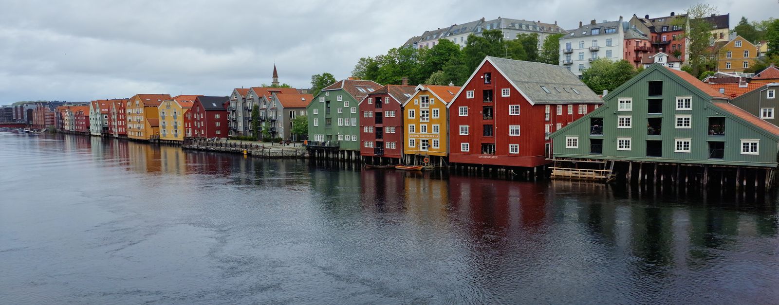 A vibrant view of colorful waterfront houses in Trondheim, Norway under overcast skies.