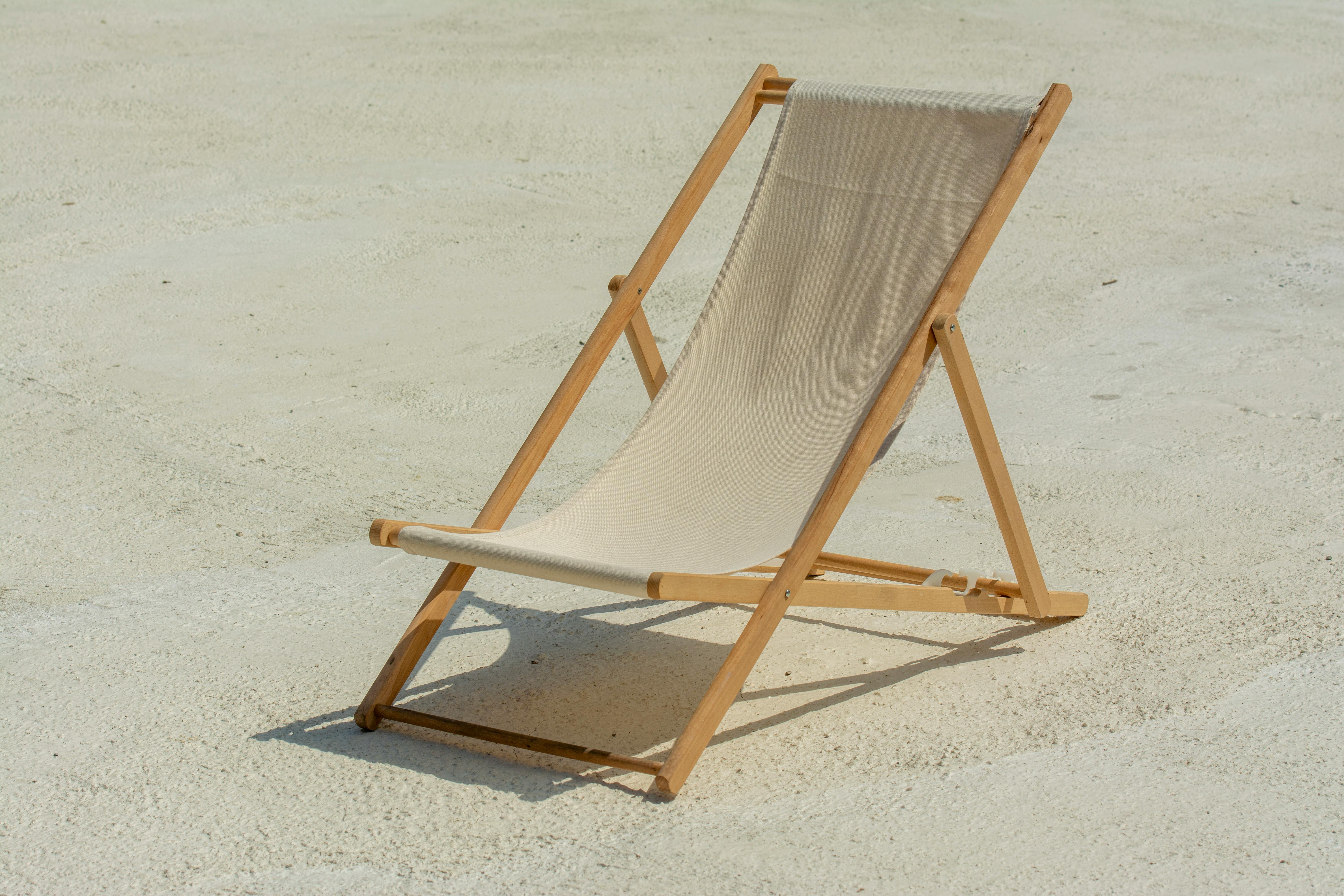 Minimalist outdoor scene featuring an empty sunlit deck chair on the beach, perfect for vacation themes.