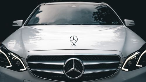 Free Close-up of the front of a white Mercedes E-Class showcasing the emblem and elegant design. Stock Photo