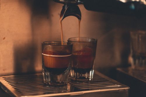 Free Close-up of hot espresso shots being brewed in a cozy café setting, showcasing rich coffee textures. Stock Photo