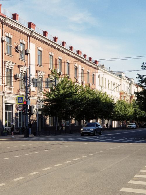 Free Picturesque urban street featuring classic European architecture and green trees. Stock Photo