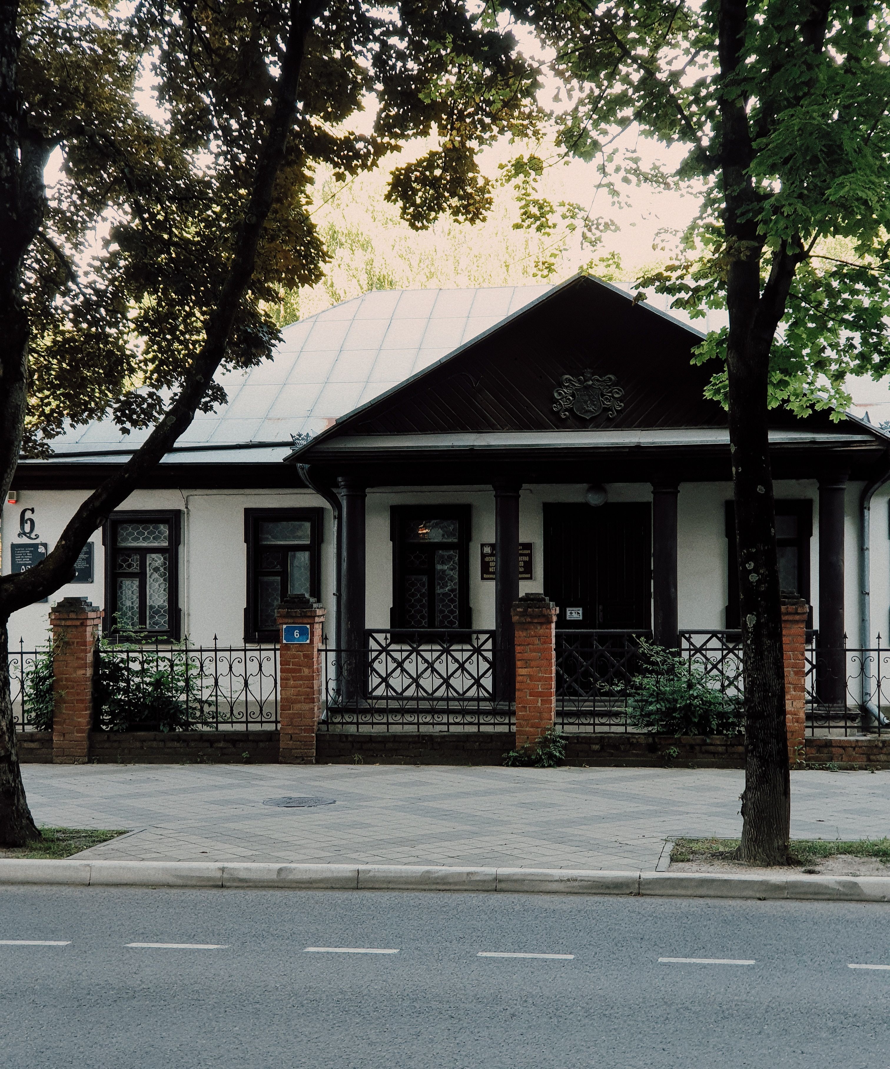 Charming wooden house with a rustic roof and lush surroundings, offering a glimpse of heritage architecture.