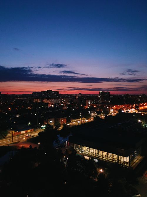 Free A breathtaking aerial view of a cityscape at twilight with illuminated streets and a colorful sky. Stock Photo