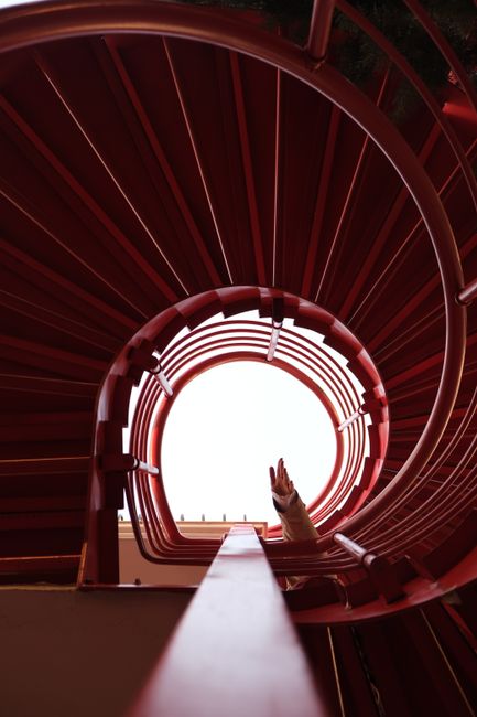 Dramatic shot of a spiral staircase with a hand reaching towards the center.