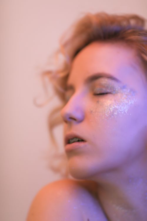 Free Close-up portrait of a woman with closed eyes adorned with glitter, creating an artistic and sensual look. Stock Photo