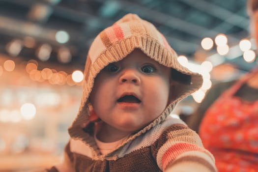 室内散景灯光下，穿着连帽衫的可爱婴儿看起来很好奇