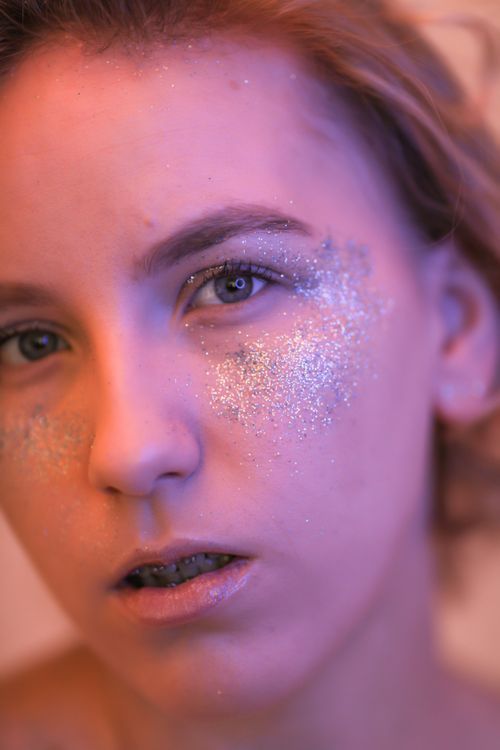 Free Artistic portrait of a woman with shimmering glitter makeup on her face in a bold close-up. Stock Photo