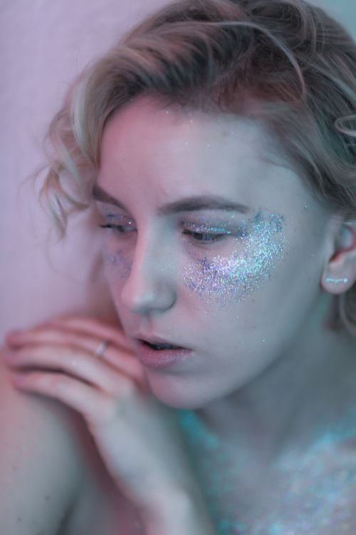 Free Close-up portrait of a woman with glitter makeup on face and shoulder. Stock Photo
