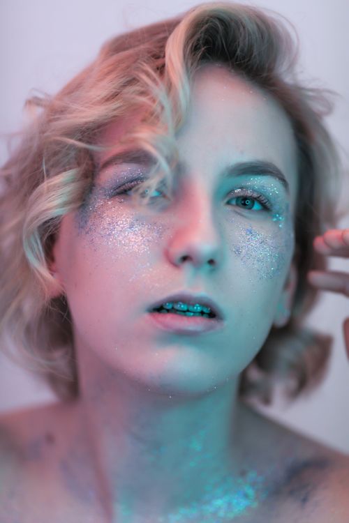 Free Close-up portrait of a woman with glitter makeup and blonde hair, evoking a dreamy artistic vibe. Stock Photo