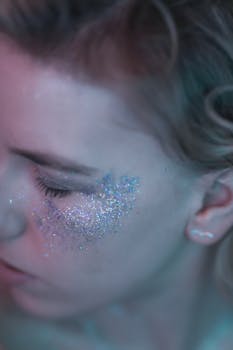 Close-up of a woman with glitter on her cheek, capturing sparkling details and serene expression.