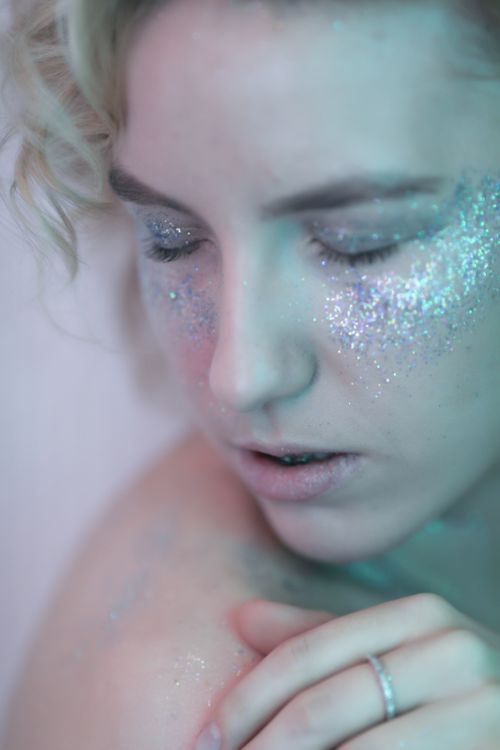 Free Close-up portrait of a woman with shimmering glitter makeup, showcasing elegance and beauty. Stock Photo