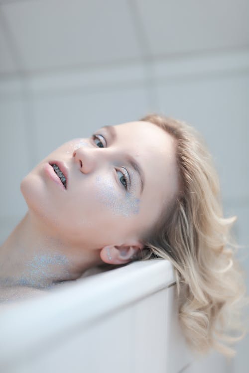 Young Woman with Glitter on Body Lying in Bathtub