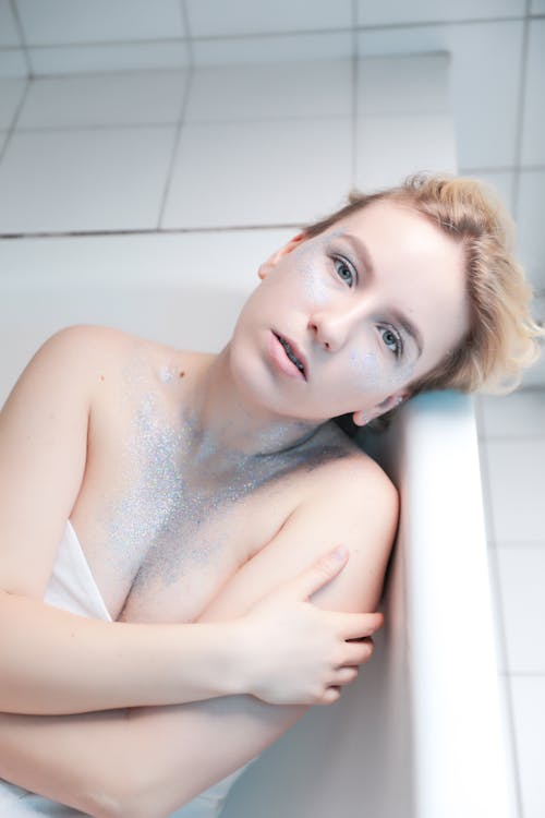 Young Woman with Glitter on Body Lying in Bathtub