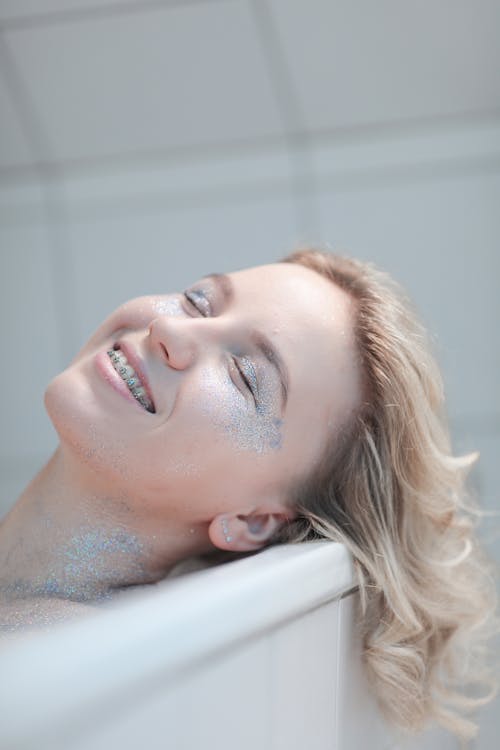 Smiling Woman with Glitter on Body Lying in Bathtub 