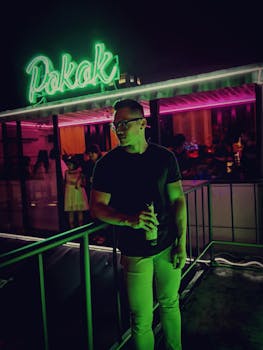 一名时尚男子在城市一家霓虹闪烁的夜总会里拿着饮料