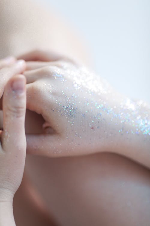 Close-up of Woman Hands with Glitter on Body