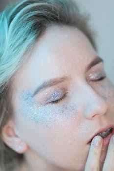 A serene close-up portrait of a woman with glitter makeup and eyes closed.