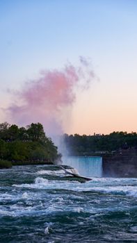 Breathtaking view of Niagara Falls with vibrant pink clouds and rushing waters at sunset, offering a scenic natural beauty.