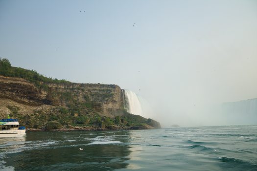 Impressive landscape view of Niagara Falls with a tour boat and cascading water.