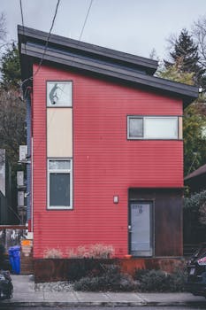 Contemporary red house with slanted roof in an urban neighborhood setting.