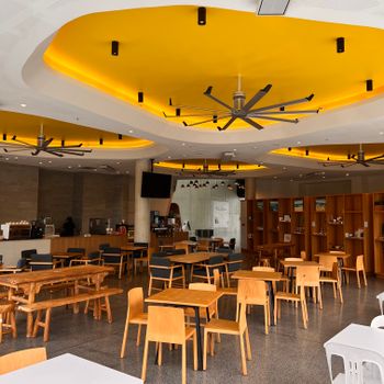 Stylish restaurant interior featuring a striking yellow ceiling design with modern furniture.