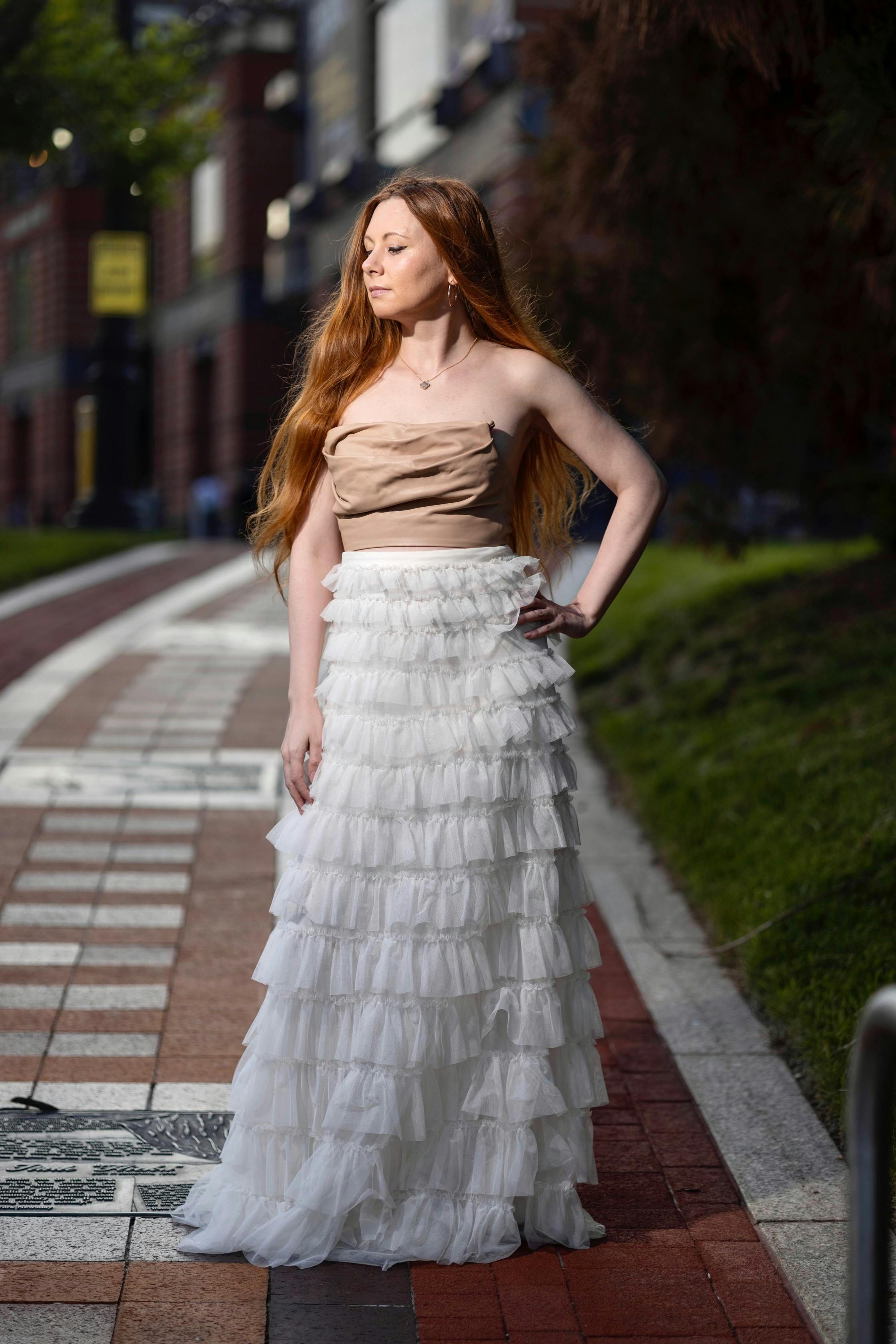 Woman Wearing a Pink Blouse and Gray Short Skirt Posing on a