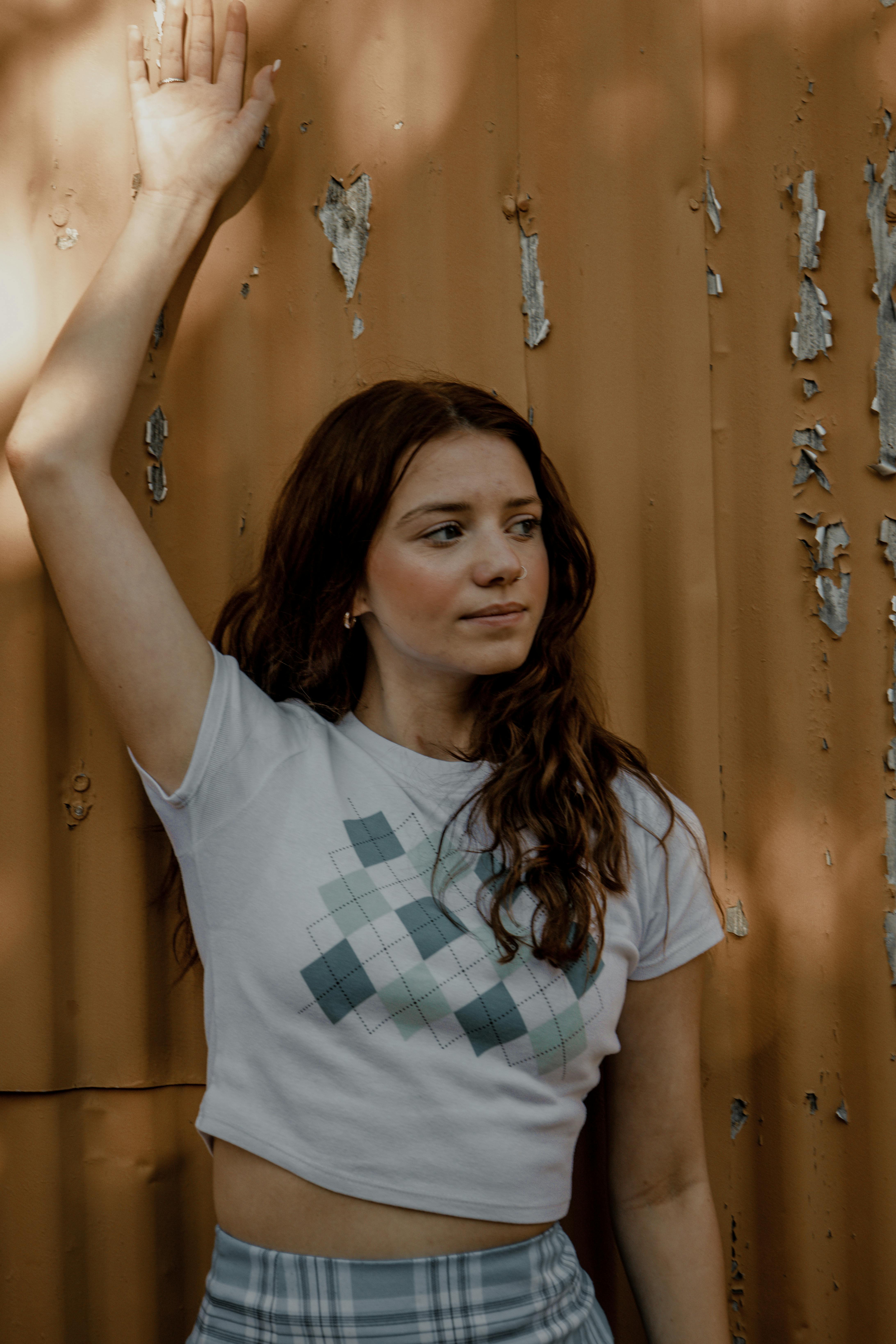 a woman leaning against a wall wearing a crop top