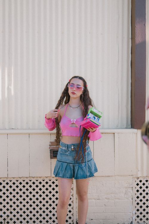 Free Young woman in a trendy Y2K outfit posing outdoors with a playful vibe. Stock Photo