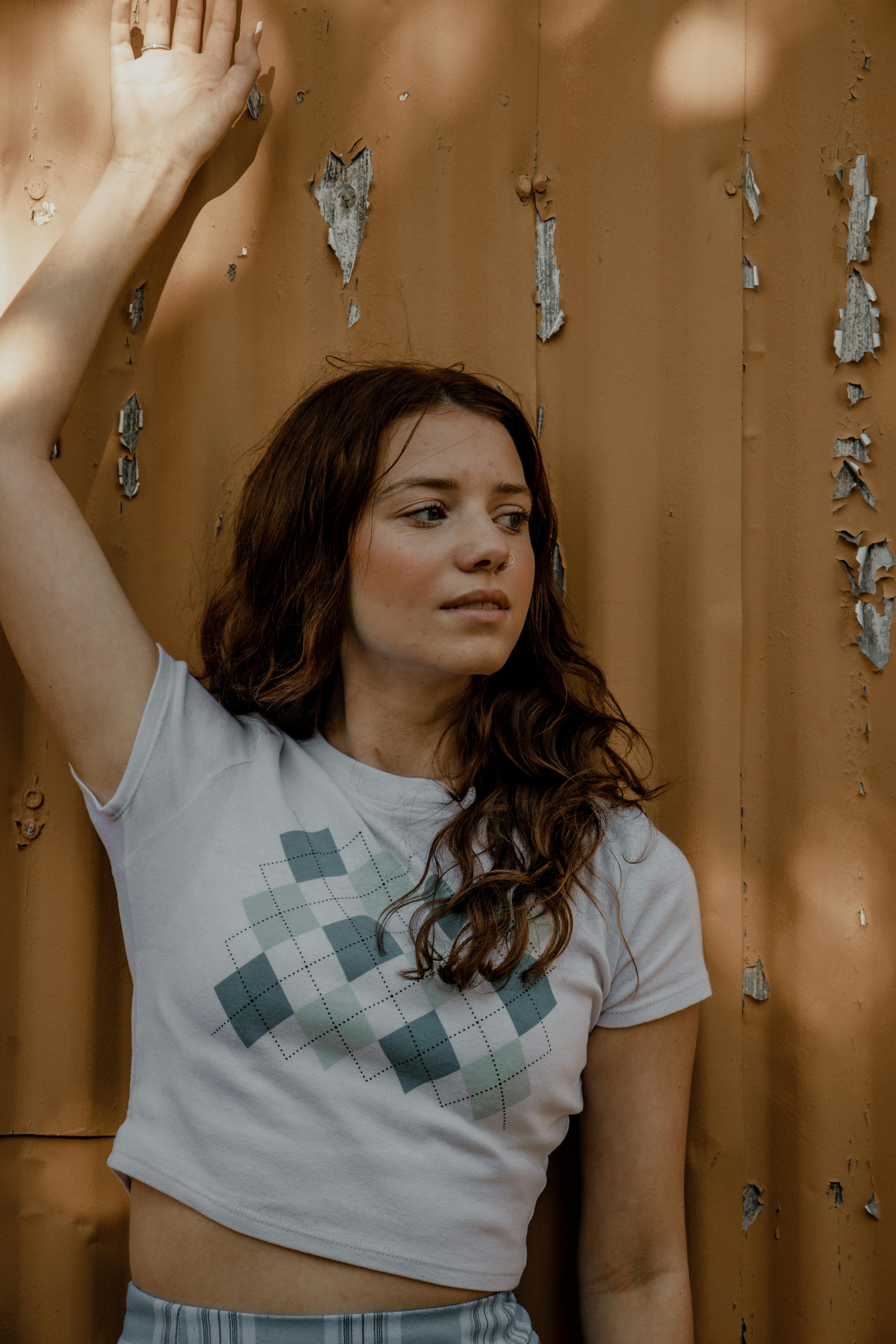 a woman leaning against a wall wearing a crop top