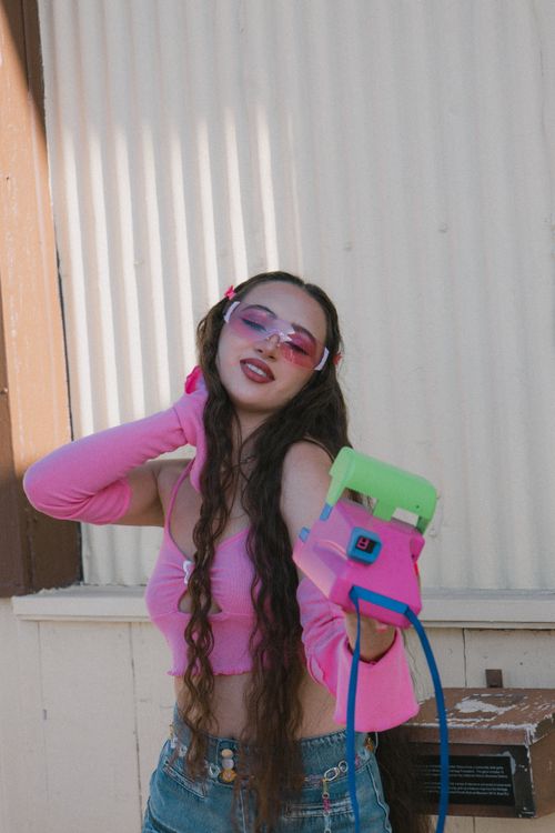 Free A stylish young woman poses with a retro phone in vibrant pink attire outdoors. Stock Photo