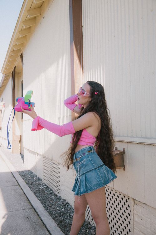 Free A young woman poses with vibrant fashion accessories in a street setting. Stock Photo