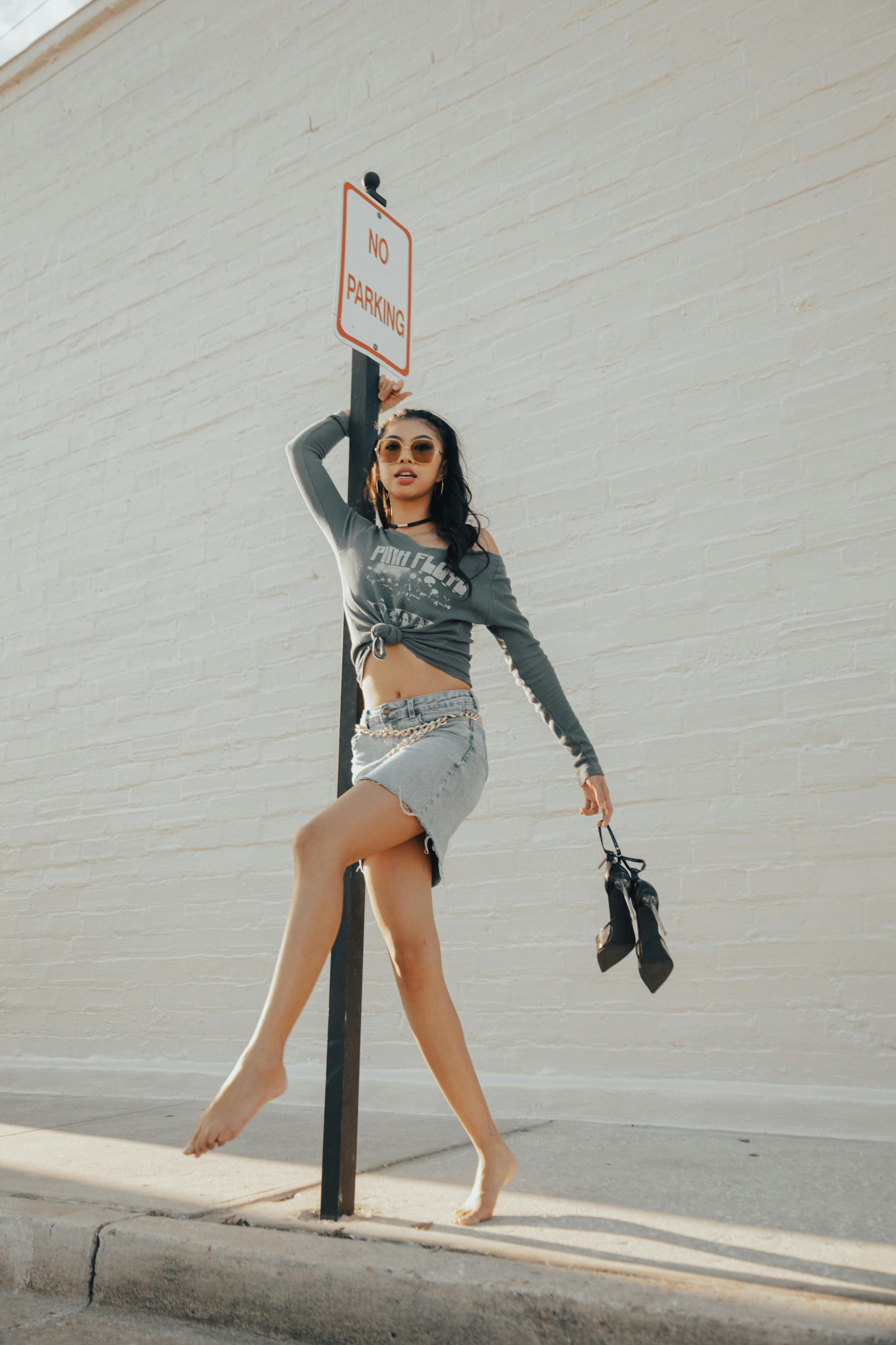 a woman in a skirt and heels is posing on a pole