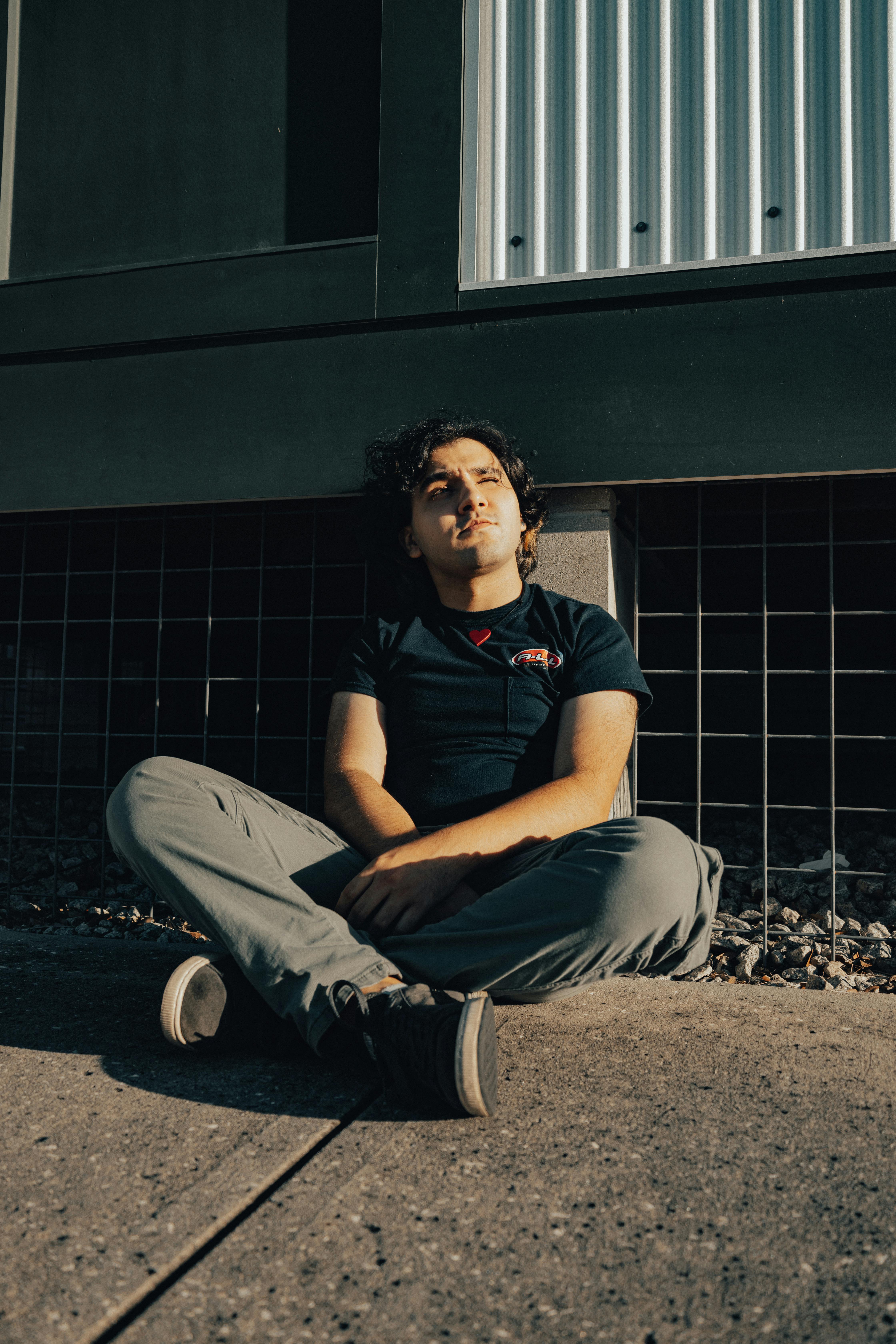 a man sitting on the ground in front of a building