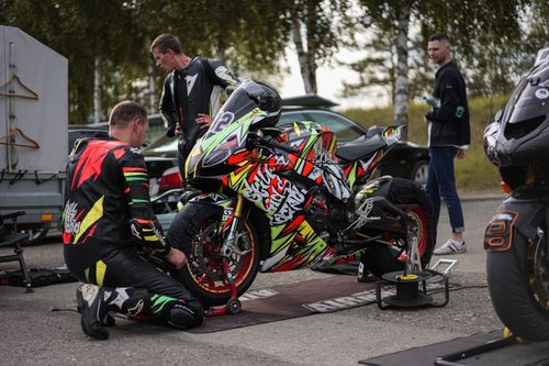 Free A vibrant motorcycle with colorful livery at a pit stop during a motorsport event. Stock Photo